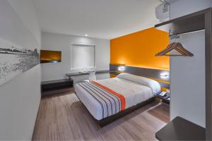 圣路易斯波托西City Express Junior by Marriott San Luis Potosi Carranza的一间卧室配有一张橙色墙壁的床