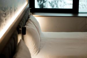 萨拉热窝Hotel Boutique Anoma的卧室配有一张带白色枕头的床,卧室设有窗户