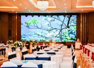 奠边府市Mường Thanh Grand Dien Bien Phu Hotel的宴会厅配有白色的桌椅和大屏幕