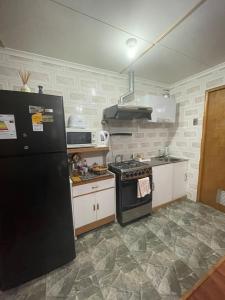 波韦尼尔Cabañas Porvenir Tierra del Fuego的厨房配有黑色冰箱和炉灶。