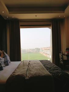 MohaliHOTEL CENTRA的一间卧室设有大窗户,享有田野美景