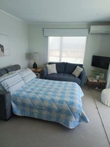 芒格努伊山Omanu Cottage的一间卧室配有一张床和一张沙发