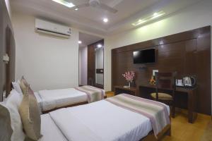 古尔冈Hotel Haris MG Road Gurugram的酒店客房设有两张床和电视。