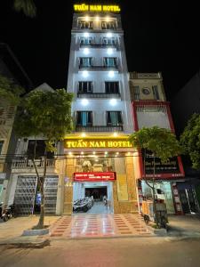 海防Tuan Nam Hotel的一座高大的白色建筑,上面有标志