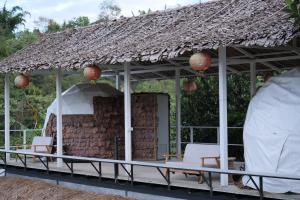 Ban Rak ThaiDome tents Hedreung Rakthai camping的一个带椅子和茅草屋顶的凉亭