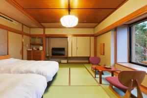 天童市泷之汤日式旅馆的一间卧室配有一张床、一张桌子和一台电视。