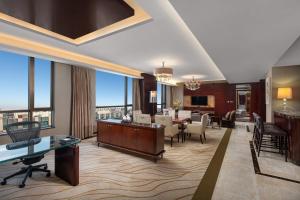 滨海新区天津滨海皇冠假日酒店的酒店客房带大堂,带桌子和椅子。