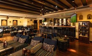 麦纳麦Mercure Grand Hotel Seef - All Suites的一间配有沙发的餐厅和一间位于客房内的酒吧