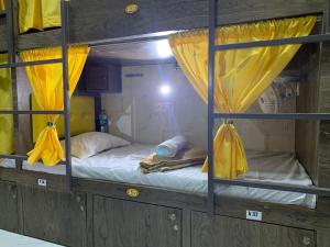 孟买Neenava Dormitory Asalpha的客房内的两张双层床,配有黄色窗帘