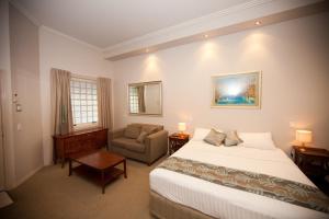 布里斯班香格里拉花园汽车旅馆的配有一张床和一把椅子的酒店客房
