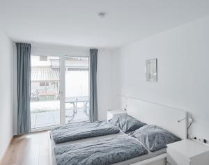 瓦滕斯Wohnen in Wattens Top 3的白色的卧室设有床和大窗户