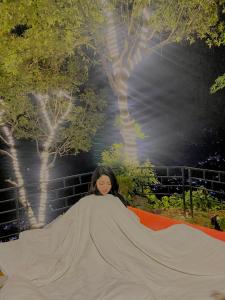 博卡拉(Sab’s villa )Forest cabin的一位女士躺在橙色地毯上,带大毯子