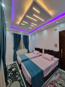 开罗Happy pyramids inn Hotel的紫色照明客房的两张床