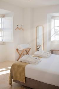 埃斯特雷莫斯Casa do Gadanha的白色的客房配有两张床和镜子