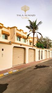 吉达Chic 3-BR Tala Almajd Villas in upscale district Alnahdah Family only的一座带两个车库门和棕榈树的建筑