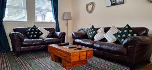 塔比特Ben Vorlich Cottage的客厅配有两张真皮沙发和一张茶几