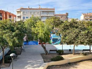 圣波拉Solecito Santa Pola. Relax and beach 4 min away的建筑前有长椅和树木的公园