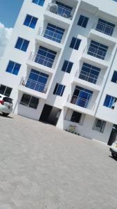 蒙巴萨Nyali cozy home的一座白色的公寓楼,前面设有停车位