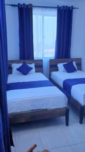 蒙巴萨Nyali cozy home的配有蓝色窗帘的客房内的两张床