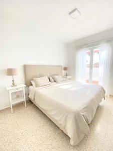 EsteponaTownhouse w/sea view & garden的白色的卧室设有白色的床和窗户。