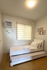 马尼拉Scandinavian design 2BR @ Ortigas, Pasig的一间卧室配有一张带窗户的床和风扇