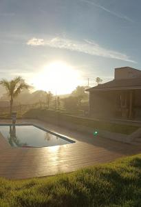 皮乌米Rancho Moreira的一座游泳池位于一座享有日落美景的房屋前