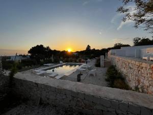 马丁纳弗兰卡Villa Ada-Trulli Puglia的落日,在石头墙上,在游泳池边