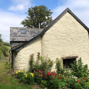 ExfordLuxury Exmoor Barn conversion with Sauna的前面有鲜花的白色建筑