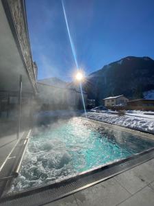 大格洛克纳山道旁富施罗密霍夫酒店的地面上带雪的热水浴池,阳光照耀