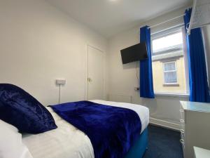 布莱克浦The New Athena Hotel的一间卧室配有一张带蓝色床单的床和一扇窗户。