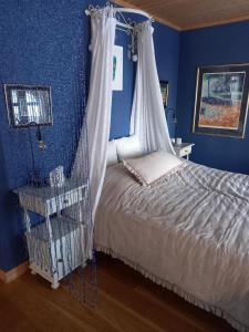 Svelvik罗尔维克别墅公寓的蓝色卧室,配有一张带天蓬的床