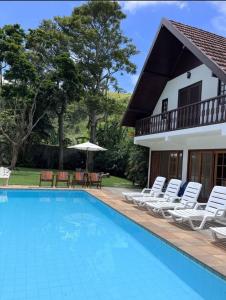 伊泰帕瓦Jardim Secreto - Itaipava的一个带椅子的游泳池以及一座房子