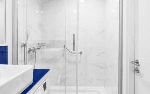 巴统Orbi City ApartHotel的带淋浴和盥洗盆的白色浴室