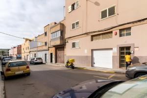 梅莱纳拉Lovely house in Gran Canaria next to the airport的一条街道,汽车停在大楼的一侧