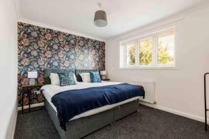 伯恩茅斯2 bedroom House-Driveway - Bournemouth Hospital - Long Stay Discounts - Lima Apartments Ltd的一间卧室配有一张蓝色床单和花卉壁纸的床