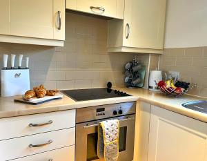 赛伦塞斯特Cosy Cotswold Home - Jacobs Cottage的厨房配有白色橱柜和炉灶烤箱。