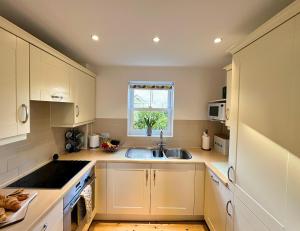 赛伦塞斯特Cosy Cotswold Home - Jacobs Cottage的厨房配有白色橱柜、水槽和窗户。