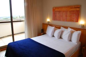 贝洛奥里藏特迪福若提拉弗林特酒店的一间卧室配有一张带蓝色毯子的床和窗户。