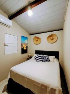费尔南多 - 迪诺罗尼亚Casa Beco do Céu的卧室配有一张床,墙上挂着两顶帽子