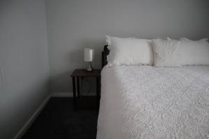 巴尔内特Charming 3Bed Home in High Barnet的一张带白色枕头的床和一张带台灯的桌子