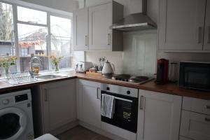 巴尔内特Charming 3Bed Home in High Barnet的厨房配有白色橱柜、水槽和洗碗机。