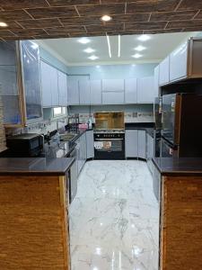 开罗شقة ألترا لوكس بالمهندسين的一间铺有大理石地板并配有白色橱柜的大厨房