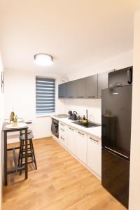 托普利察MAT Apart的厨房配有白色橱柜和黑色冰箱。