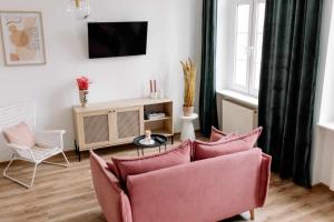 克维曾Apartament Pastelowy Kwidzyn的客厅配有粉红色的沙发和电视
