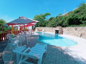 索里托斯Punta Cocos Beach Casitas的一个带椅子和桌子的游泳池以及一把遮阳伞