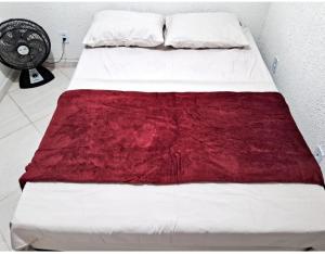 萨夸雷马Mini Casa Aconchegante的一张带红色毯子和风扇的床