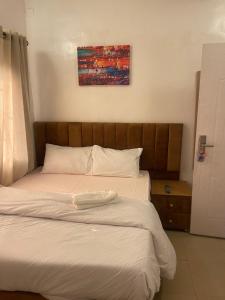 拉各斯Mph mini的一张铺有白色床单的床和木制床头板
