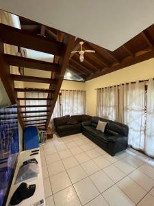 马利西亚斯B12 Casa em Maresias condomínio a 50 metros da praia的客厅设有黑色真皮沙发和木制天花板。