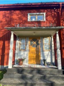 于默奥Gamla gården i Ersmark Umeå的红色和白色的房子,有黄色的门