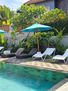乌布Chandi Hotel Ubud的一组椅子和一把遮阳伞,位于游泳池旁